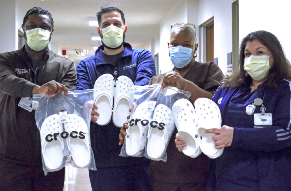 Mental health technician James Carter, nurse Steven Grotkowski, mental health technician Cheryl Echols, and nurse Meg Spicer pose while each holding a pair of donated white Crocs clogs.